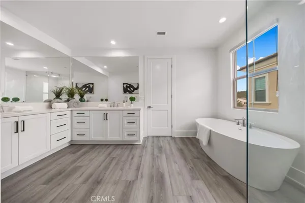 a spacious bathroom with a double vanity sink a mirror and a bathtub