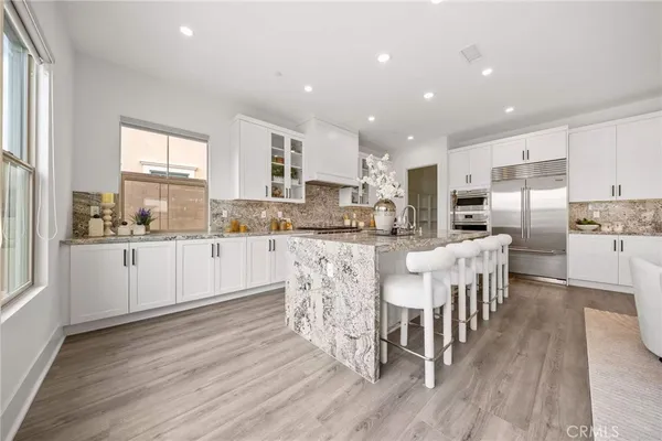 a kitchen with stainless steel appliances kitchen island granite countertop a stove a refrigerator a sink a dining table and chairs