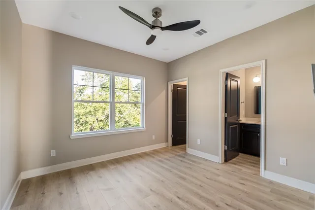 a view of empty room with wooden floor and ceiling fan