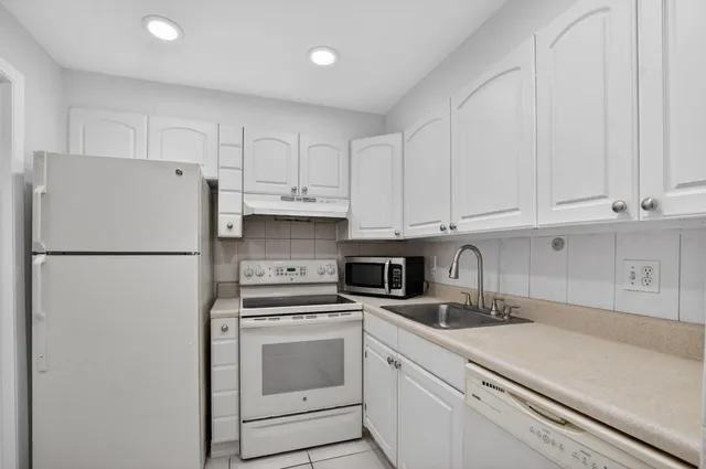 a kitchen with refrigerator a stove a sink and cabinets