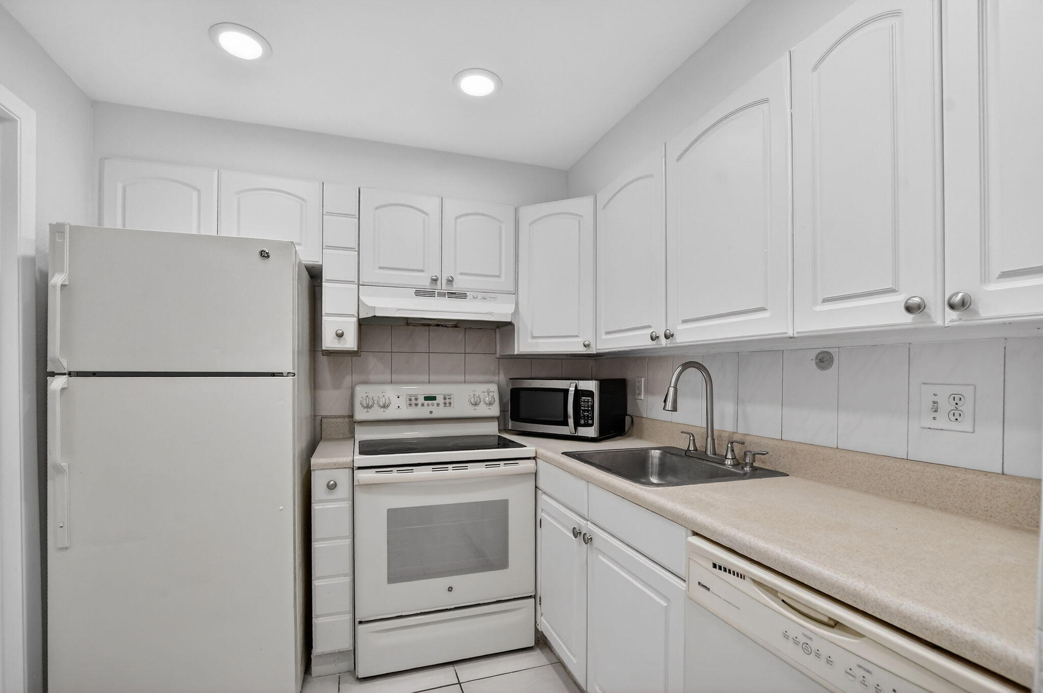 644 Northwest 13th Street, Unit 110 Boca Raton, FL 33486 - Photo 7 of 24 a kitchen with refrigerator a stove a sink and cabinets