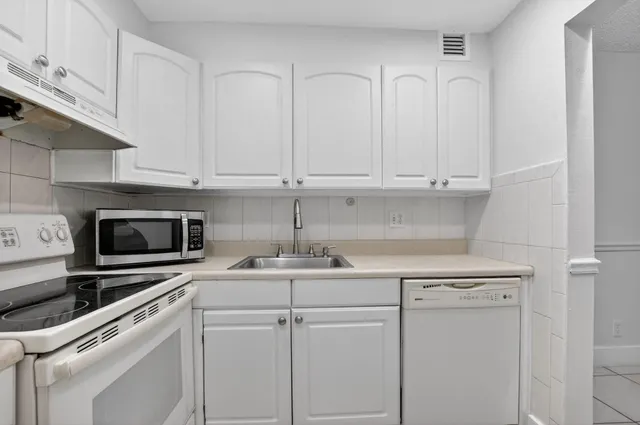 a kitchen with white cabinets and white appliances