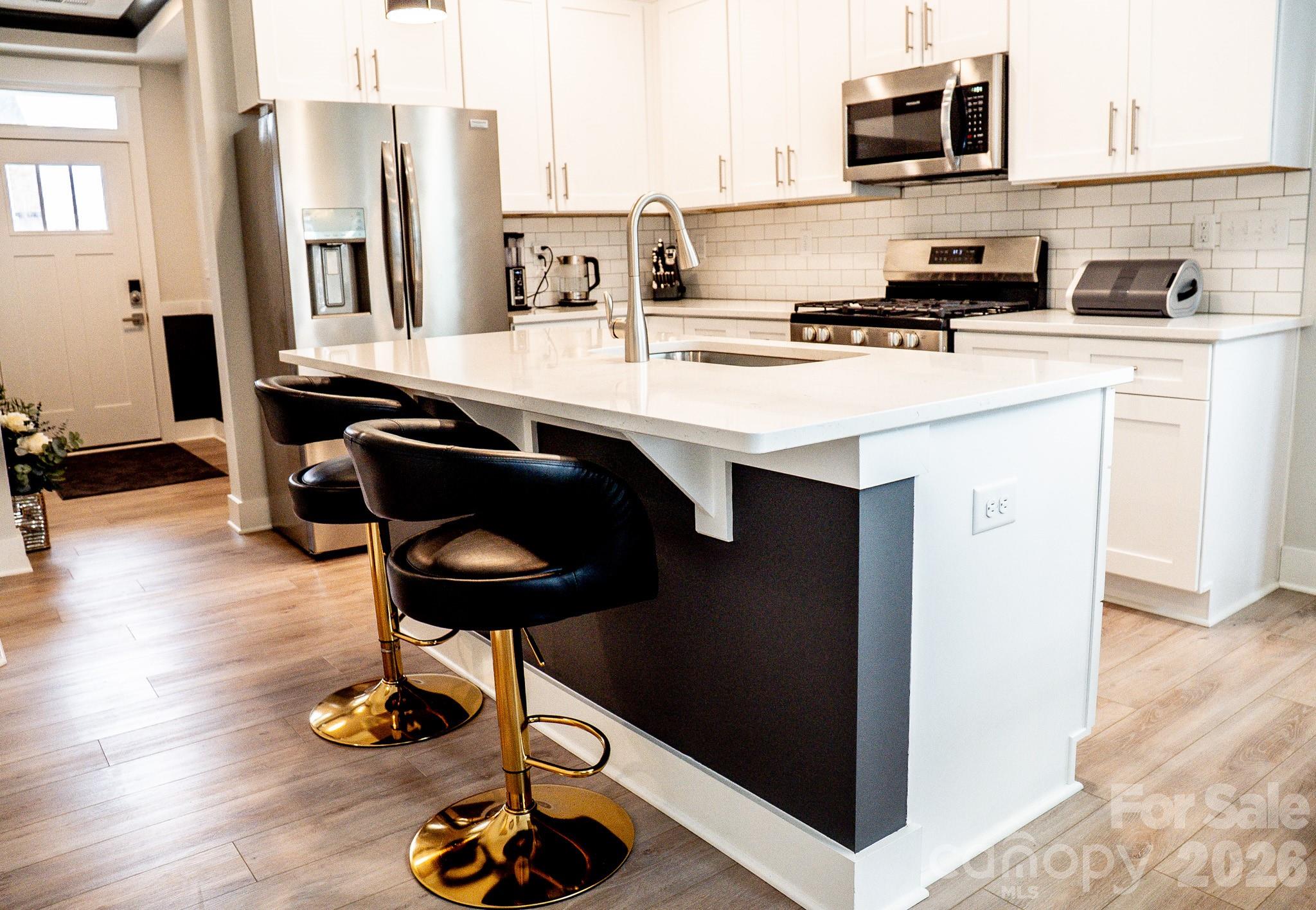 6288 Culbert Street Harrisburg, NC 28075 - Photo 7 of 40 a kitchen with stainless steel appliances kitchen island granite countertop a refrigerator a stove a sink dishwasher and white cabinets with wooden floor