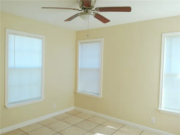 an empty room with windows and fan
