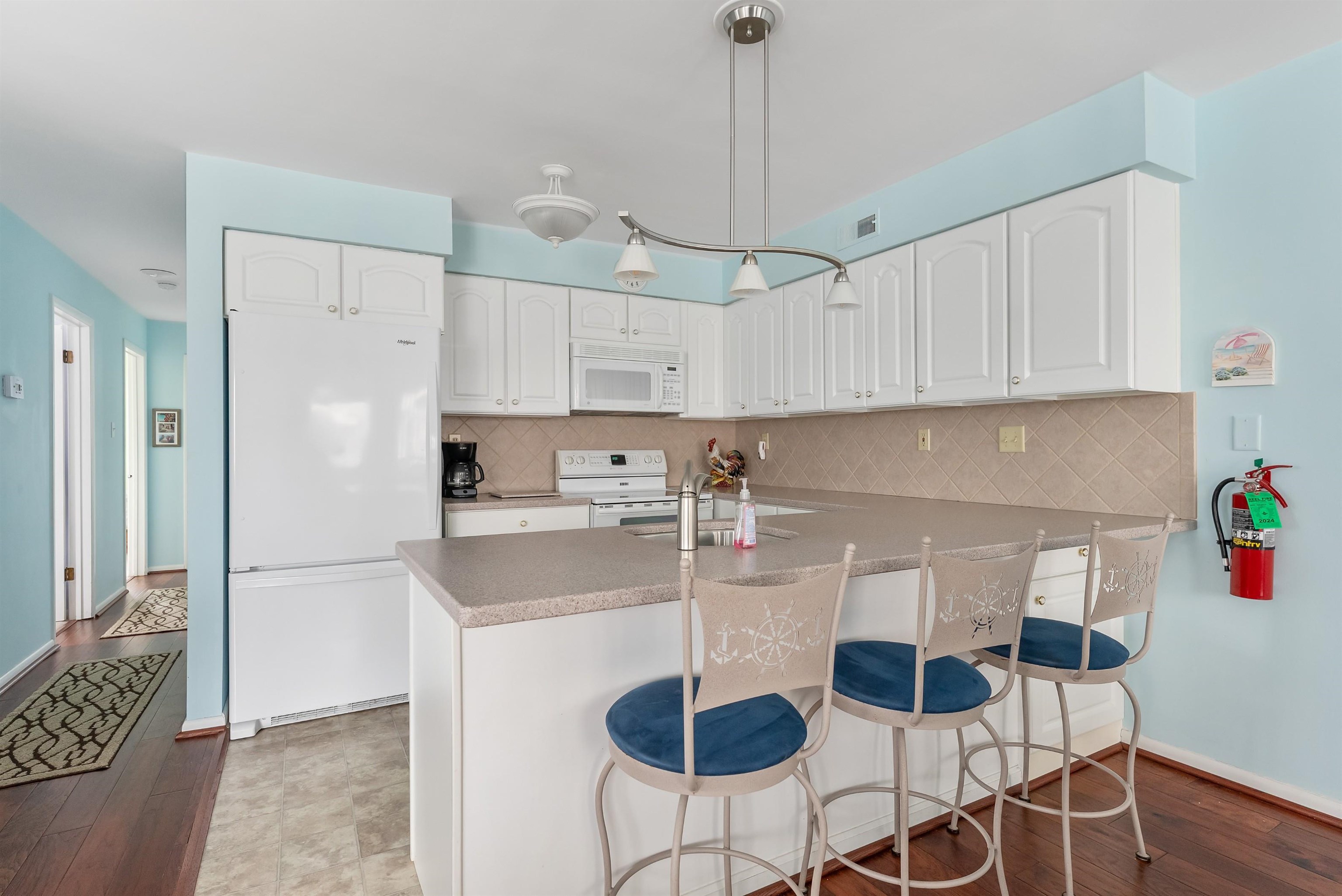 280 79th Street, Unit 1 Avalon, NJ 08202 - Photo 11 of 21 a kitchen with stainless steel appliances granite countertop a sink a refrigerator a stove a dining table and chairs with wooden floor