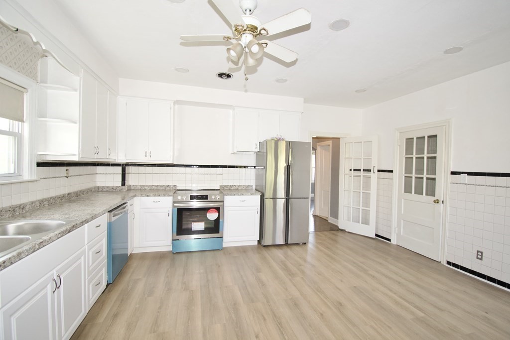 102 Florence Street Springfield, MA 01105 - Photo 11 of 30 a kitchen with stainless steel appliances granite countertop a refrigerator a sink dishwasher a stove and white countertops with wooden floor