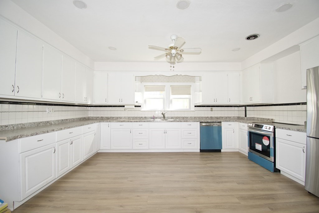 102 Florence Street Springfield, MA 01105 - Photo 13 of 30 a large white kitchen with a sink dishwasher stove and white cabinets with wooden floor