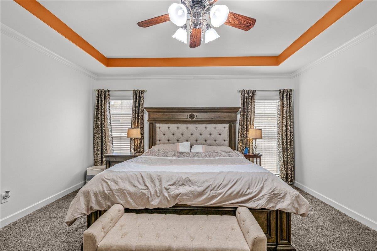 744 Southern Home Road Collierville, TN 38017 - Photo 8 of 24 Tray ceiling with crown molding and recessed orange accents, overhead ceiling fan with light fixture, and two windows with blinds and patterned drapes