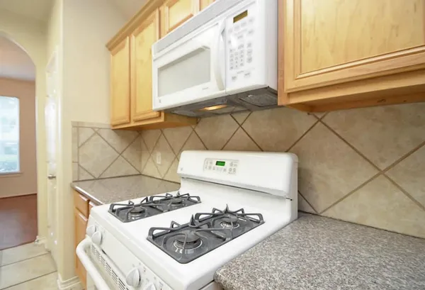 an empty room with a chandelier fan and windows