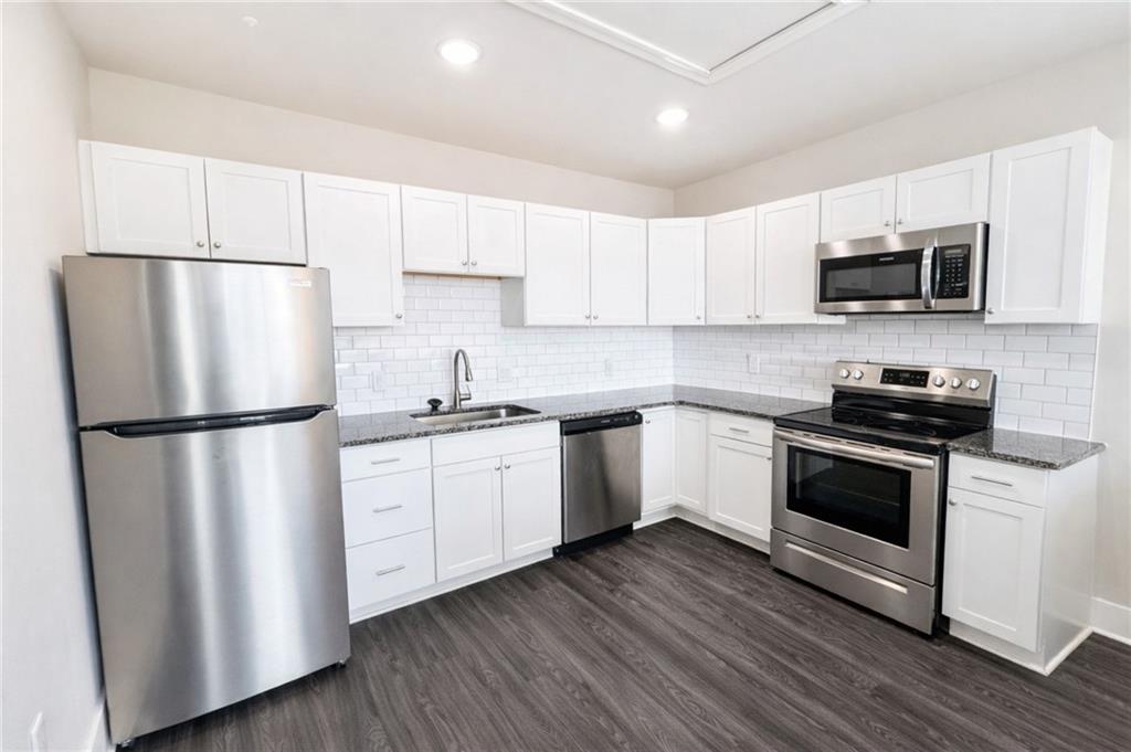 161 Mangum Street Southwest, Unit 204 Atlanta, GA 30313 - Photo 14 of 24 a kitchen with white cabinets white stainless steel appliances and wooden floors
