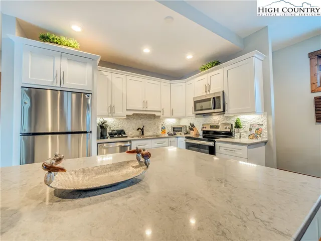 a kitchen with kitchen island a stove a sink a refrigerator a counter top space and cabinets