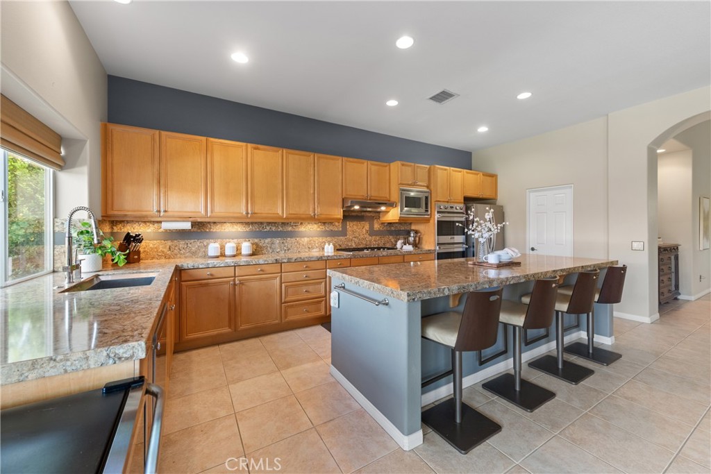 70 Rocio Court Palm Desert, CA 92260 - Photo 16 of 40 a kitchen with kitchen island granite countertop wooden cabinets a dining table and chairs
