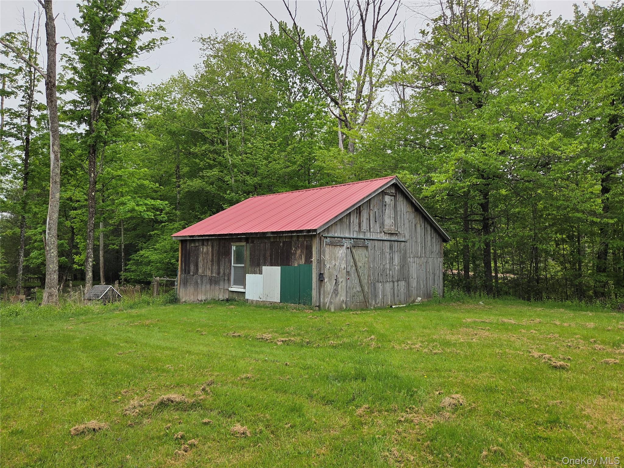 125 Zimmerman Road Loch Sheldrake, NY 12759 - Photo 38 of 43 a small barn in front of a house with a big yard and large trees