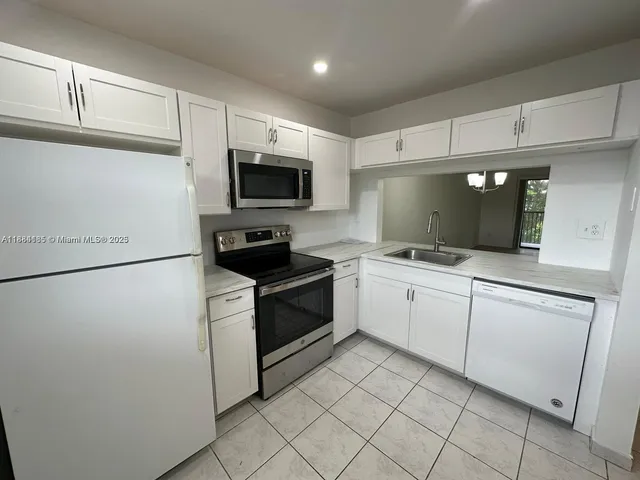 a kitchen with white cabinets stainless steel appliances and a counter space