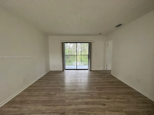 a view of an empty room with wooden floor and window