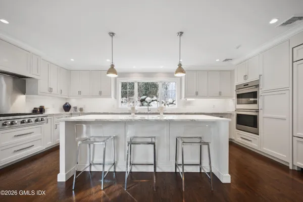 a kitchen with stainless steel appliances granite countertop a stove a sink dishwasher a refrigerator white cabinets with wooden floor
