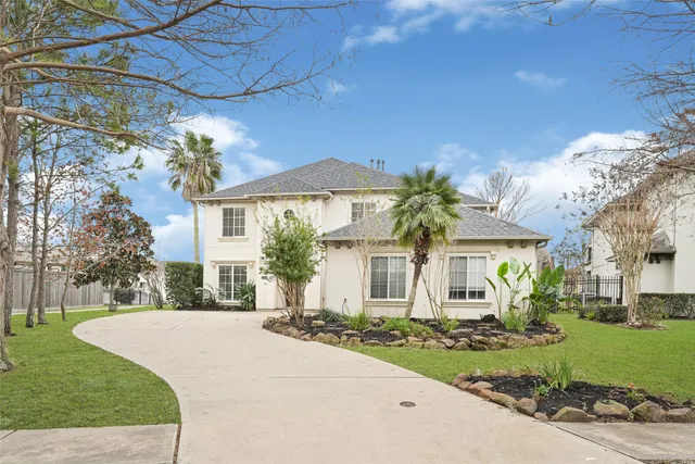a front view of a house with a garden and trees