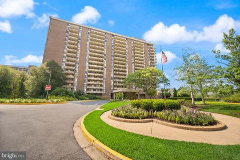 a front view of a multi story residential apartment building with yard and green space