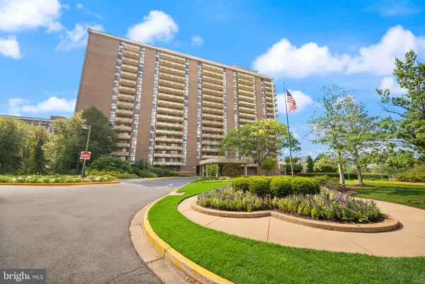 a front view of a multi story residential apartment building with yard and green space