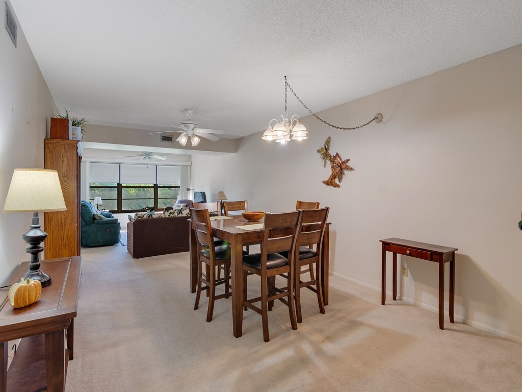 27 Plantation Drive, Unit 202 Vero Beach, FL 32966 - Photo 1 of 30 a view of a dining room and kitchen with furniture and a chandelier