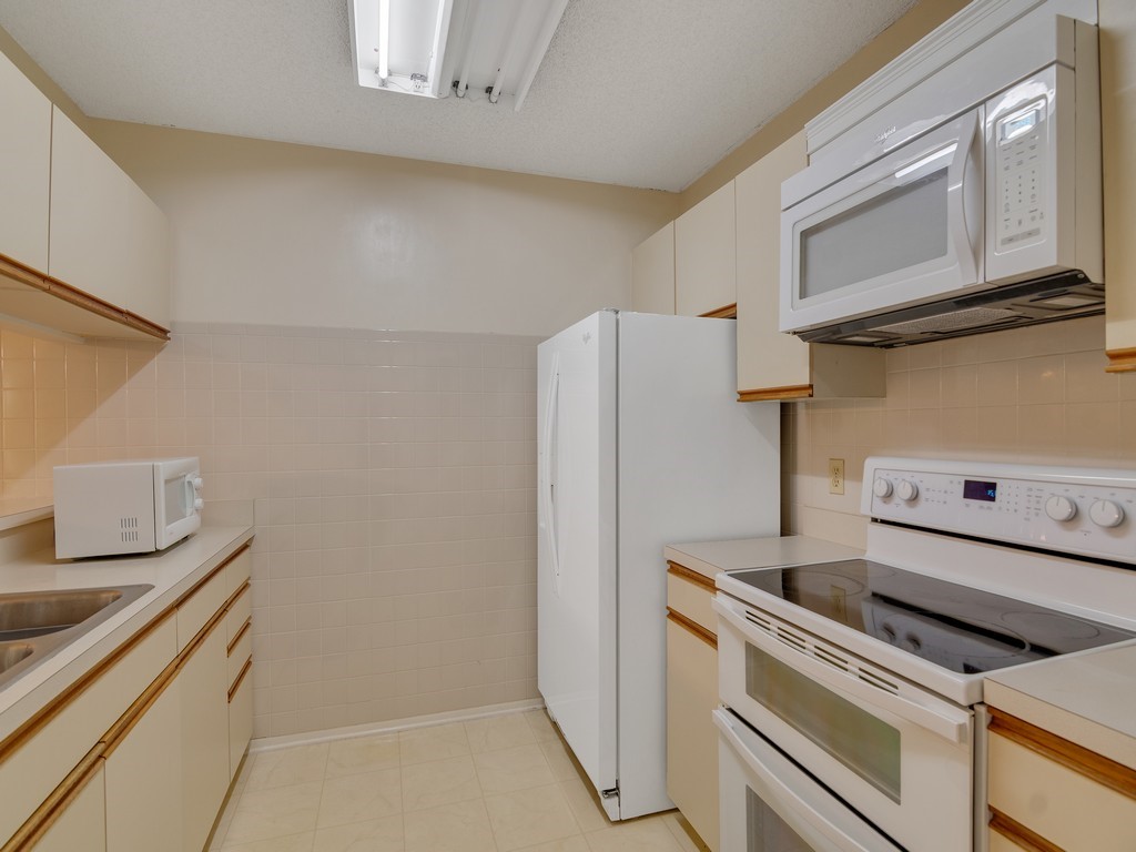 27 Plantation Drive, Unit 202 Vero Beach, FL 32966 - Photo 8 of 30 a kitchen with a stove and a refrigerator