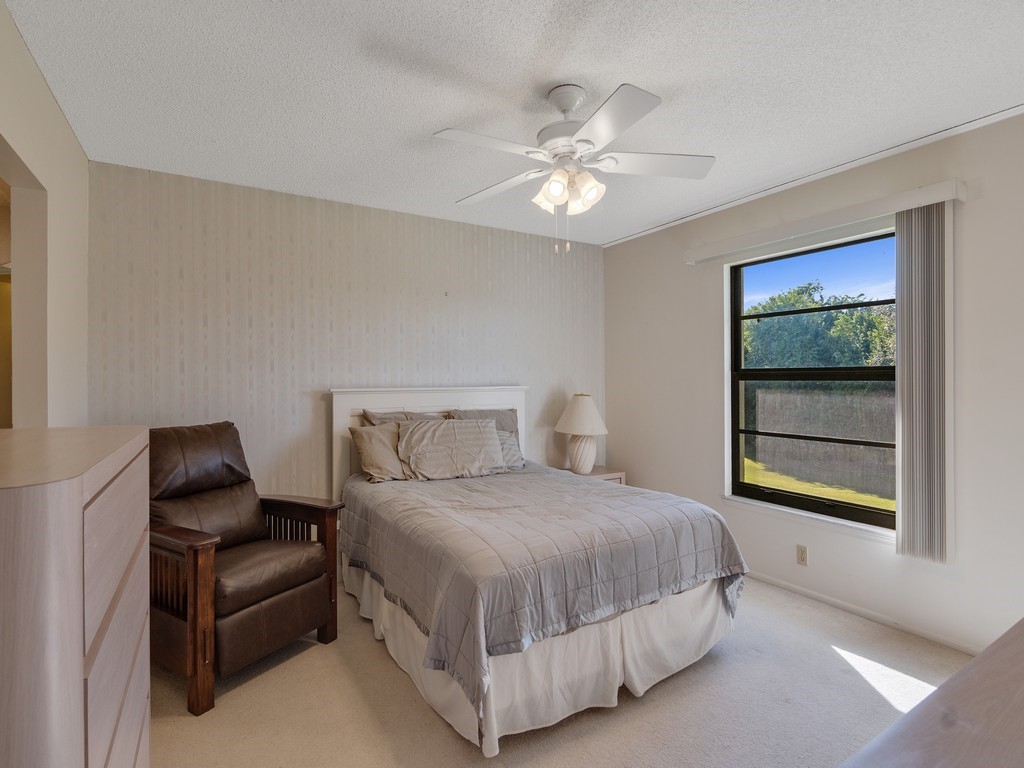 27 Plantation Drive, Unit 202 Vero Beach, FL 32966 - Photo 10 of 30 a bedroom with a bed and a chandelier