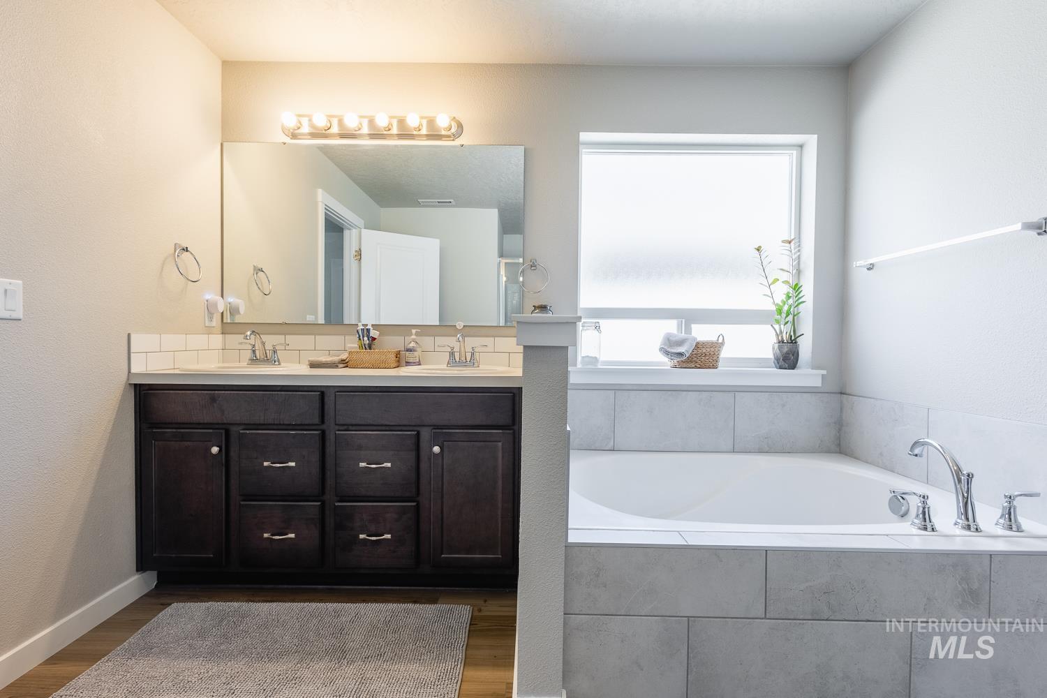 12623 Shadow Peak Street Caldwell, ID 83607 - Photo 33 of 50 Dual vanity with dark wood-finish cabinetry, white countertop, and subway tile backsplash