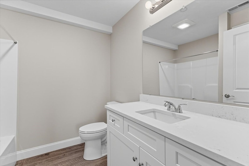 202 Central Street, Unit I Avon, MA 02322 - Photo 18 of 19 a bathroom with a granite countertop sink a toilet and a mirror