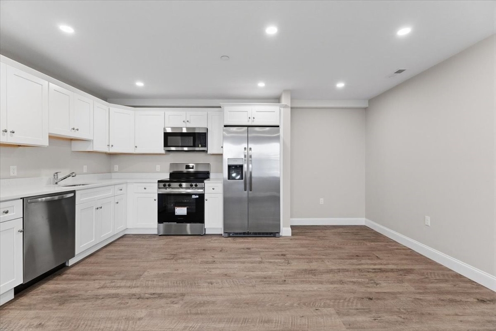 202 Central Street, Unit I Avon, MA 02322 - Photo 6 of 19 a kitchen with granite countertop a refrigerator and a stove top oven