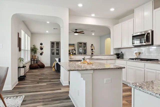 a kitchen with stainless steel appliances granite countertop a lot of counter space and wooden floors