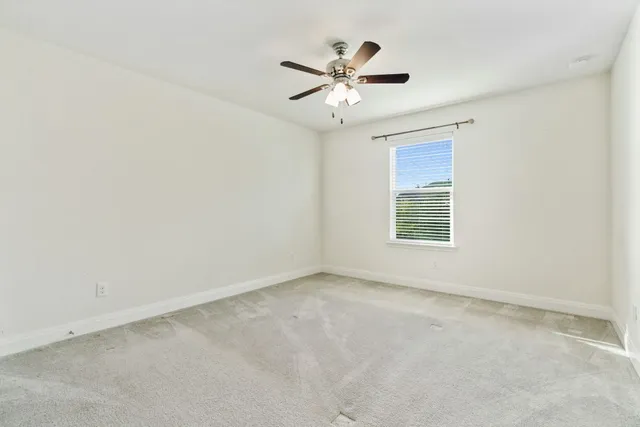 an empty room with windows and ceiling fan