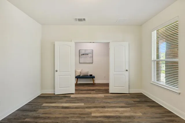 a view of empty room with wooden floor and fan