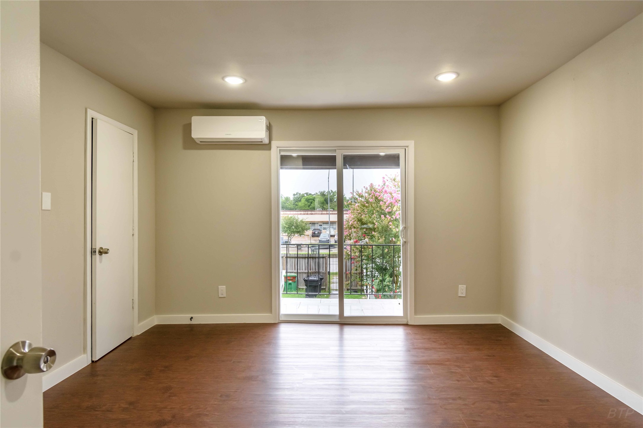 11933 Beechnut Street Houston, TX 77072 - Photo 7 of 9 an empty room with wooden floor and windows with curtains