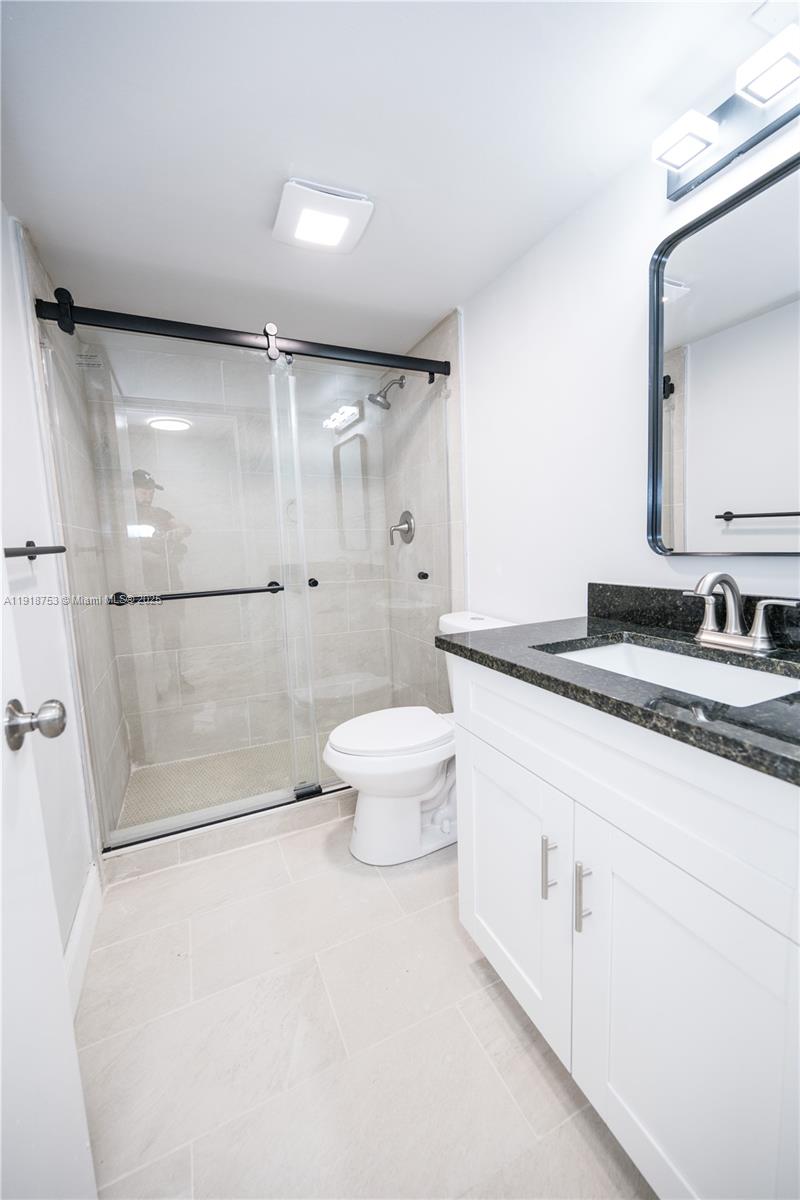 755 Dotterel Road, Unit 1301 Delray Beach, FL 33444 - Photo 11 of 15 a bathroom with a granite countertop sink a toilet and a shower
