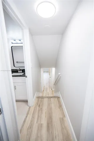 a view of kitchen and empty room with wooden floor