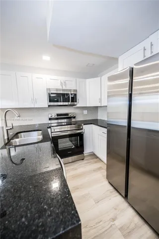 a kitchen with kitchen island a counter top space cabinets and stainless steel appliances