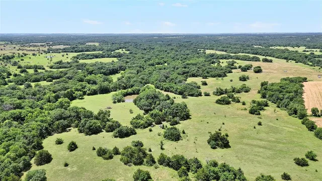 an aerial view of residential houses with outdoor space and trees all around