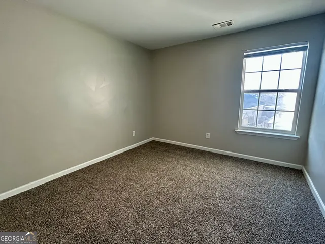 a view of an empty room with a window and a kitchen