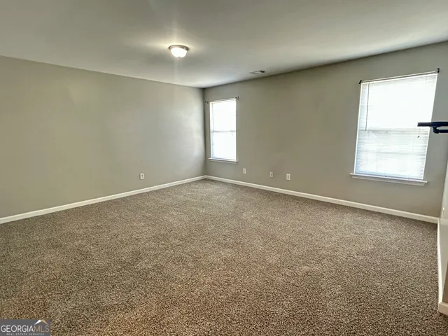 an empty room with a chandelier fan and windows