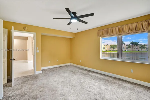 a view of an empty room with closet and a ceiling fan