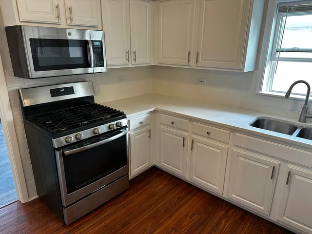 a kitchen with granite countertop cabinets stainless steel appliances and wooden floor