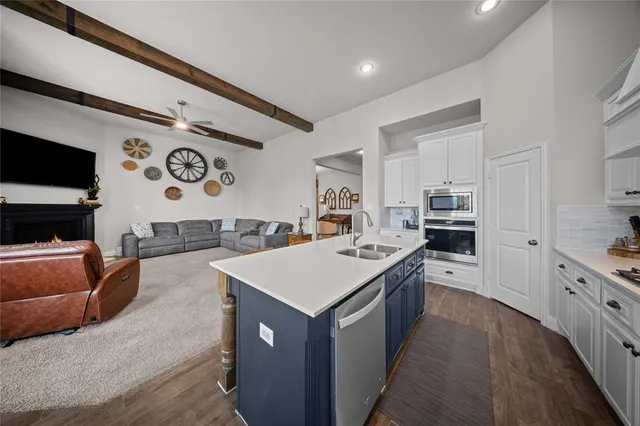 a large kitchen with stainless steel appliances a stove a sink a refrigerator and dishwasher with wooden floor