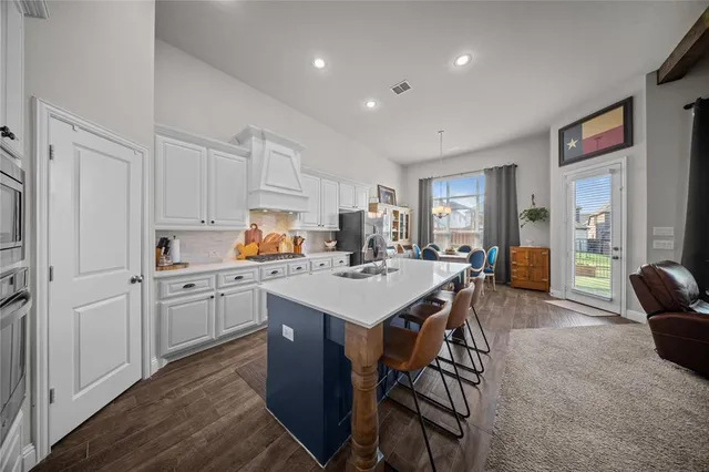 a kitchen with a sink chairs and white cabinets