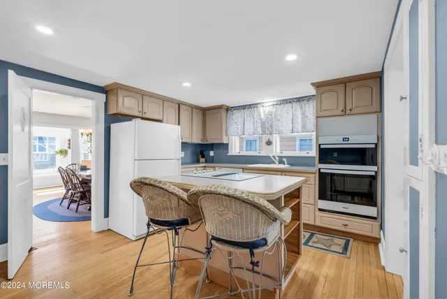 a kitchen with granite countertop a refrigerator a stove a sink dishwasher and white cabinets with wooden floor