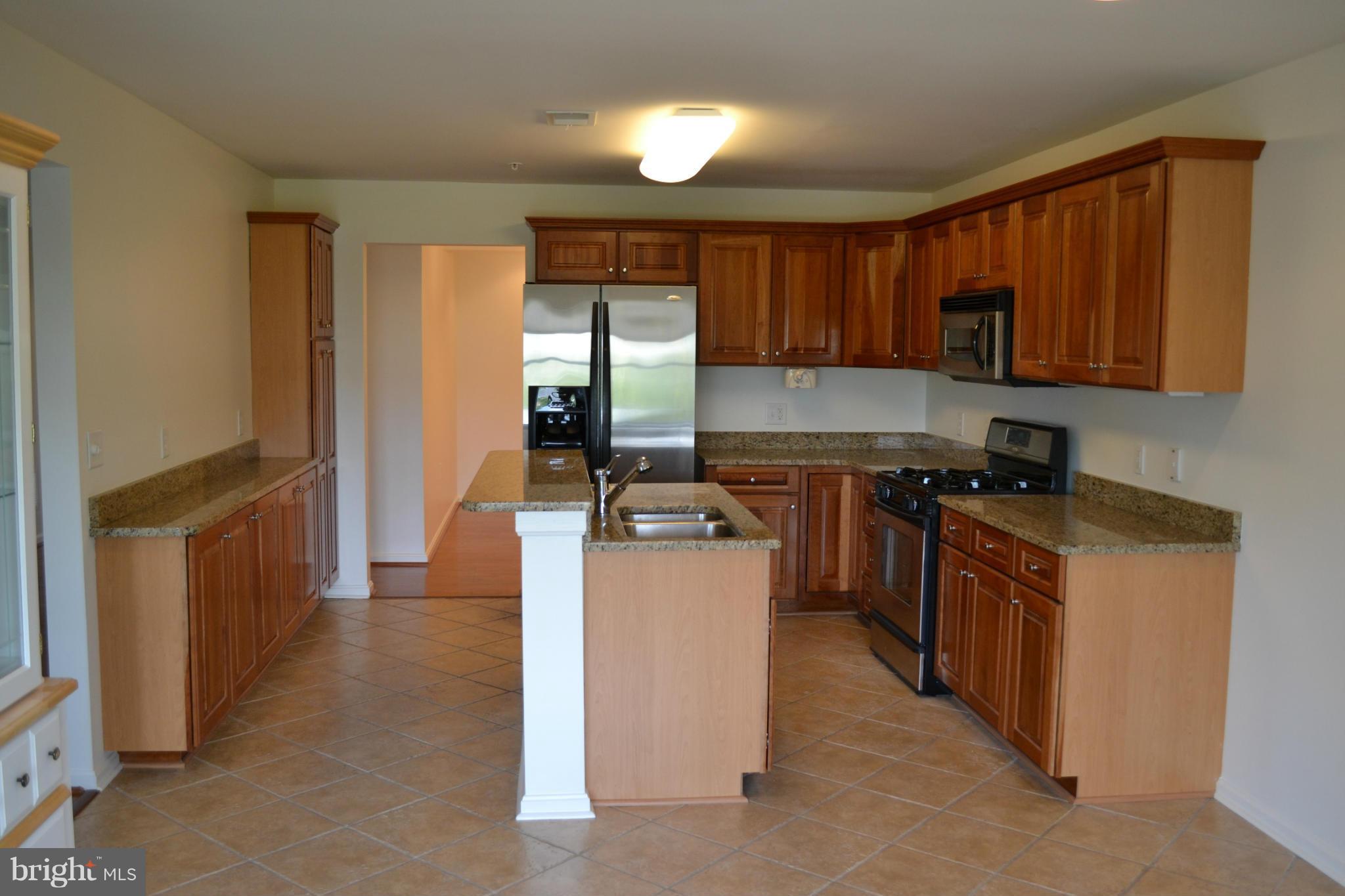 12246 Roundwood Road, Unit 405 Lutherville-Timonium, MD 21093 - Photo 5 of 16 a kitchen with stainless steel appliances granite countertop a stove a sink and a refrigerator