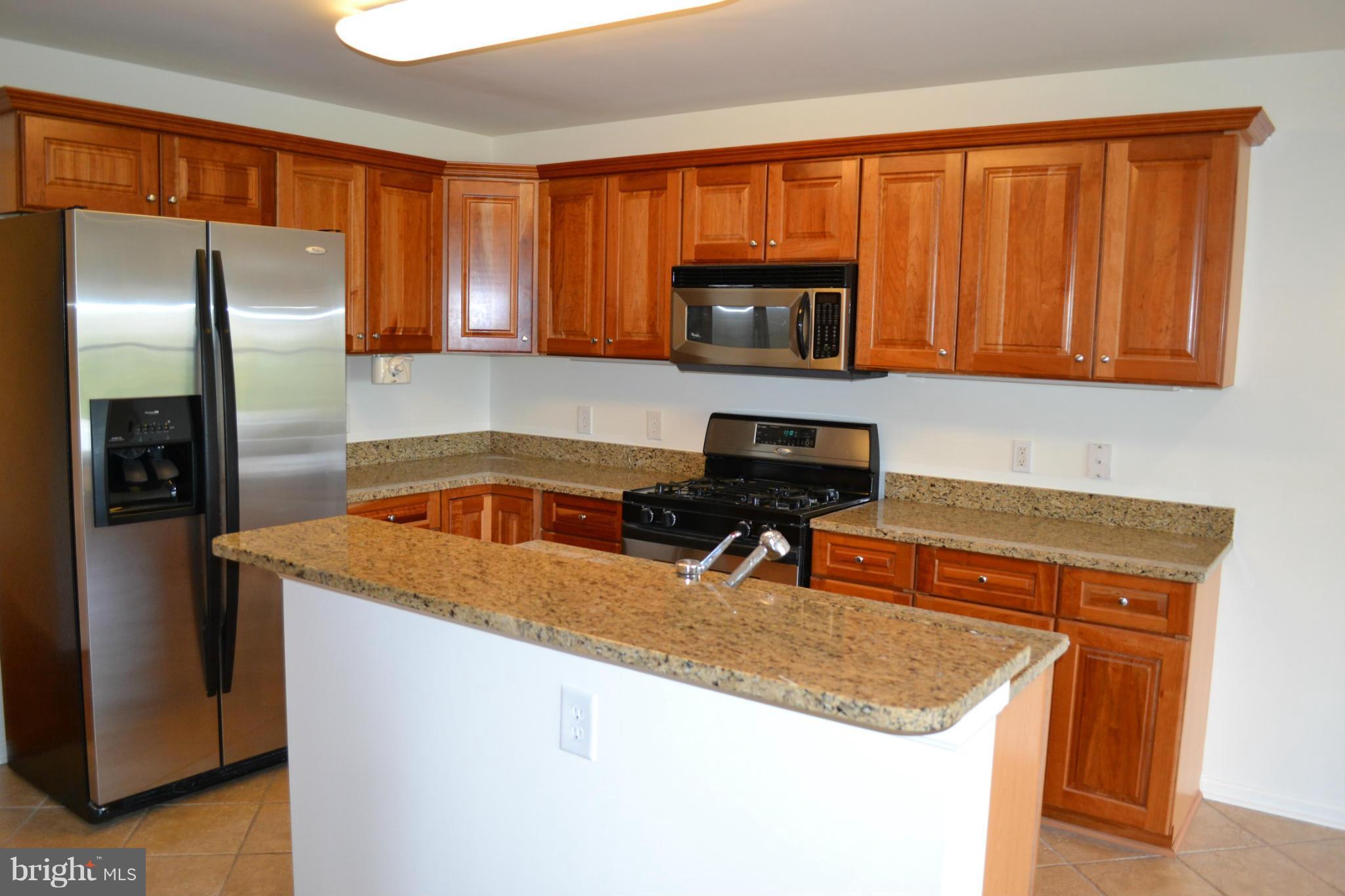 12246 Roundwood Road, Unit 405 Lutherville-Timonium, MD 21093 - Photo 7 of 16 a kitchen with stainless steel appliances granite countertop a sink stove and refrigerator