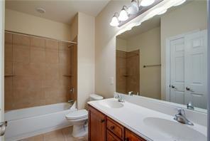 4679 Edith Street Plano, TX 75024 - Photo 29 of 34 Bathroom featuring a dual-sink vanity with wood-finish cabinetry, a large wall-mounted mirror, and a tub-shower combination with full-height tile surround