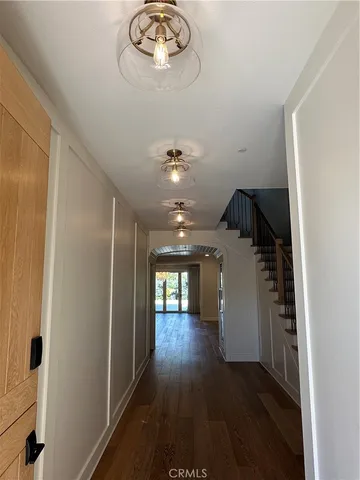 a view of a hallway with wooden floor and chandelier