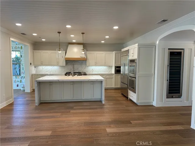 a large kitchen with stainless steel appliances kitchen island a large counter top and a stove top oven