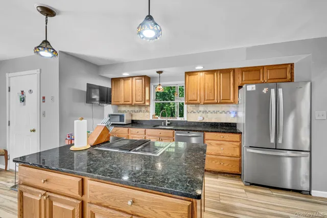 a kitchen with stainless steel appliances granite countertop a refrigerator a stove and a wooden floors